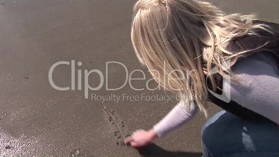junge Frau schreibt im Sand am Meer das Wort "Love"