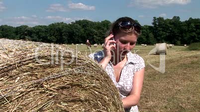 Junge Frau telefoniert im Freien auf dem Feld