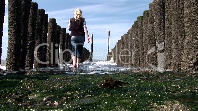 Blonde junge Frau spaziert am Strand