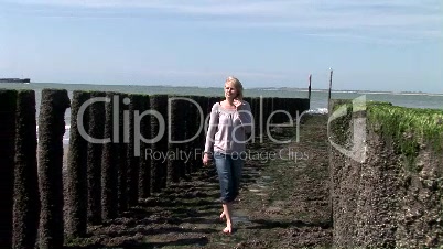 Blonde junge Frau spaziert am Strand