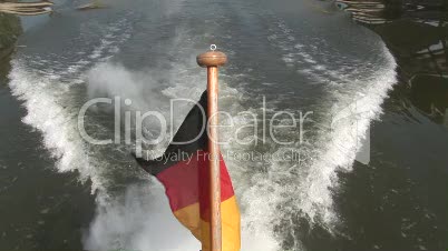 Heckwelle eines Motorbootes mit deutscher Heckflagge