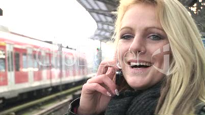 Frau telefoniert am Bahnhof