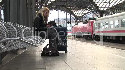 Blonde Frau liest ein Buch am Bahnhof