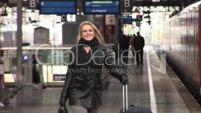Frau mit Koffer geht über Bahnsteig (Slow Motion)