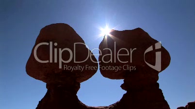 Sun peeks behind rock formations, time lapse