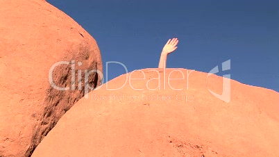Hand waving behind rock