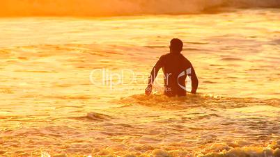 Surfer läuft mit seinem Surfbrett durch Wellen ins Meer