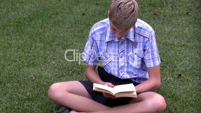 boy on a grass reads the book.