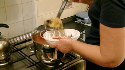 woman pours a borsch in plates.