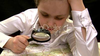 girl with a magnifier studies a map of Europe.