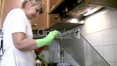 woman in gloves cleans a gas stove.