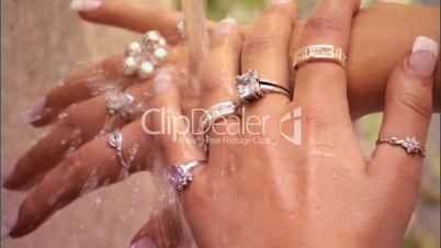 Frauenhände mit Ringen am Finger unter einem Wasserstrahl