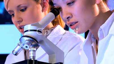 Zwei Ärztinnen schauen abwechselnd durch ein Mikroskop