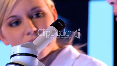 Nahaufnahme - Zwei Ärztinnen arbeiten abwechselnd durch ein Mikroskop