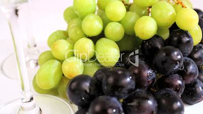 Blaue und grüne Trauben neben Weingläsern