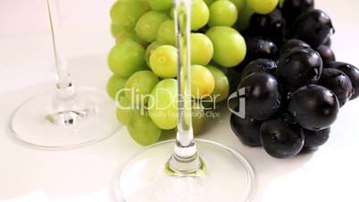 Blaue und grüne Trauben neben Weingläsern