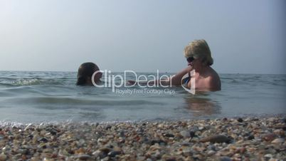 daughter and mum lay joyful in sea water.