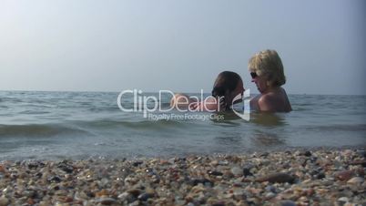 daughter and mum lay joyful in sea water.