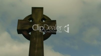 Time lapse clouds flowing past a cross in a cemetery