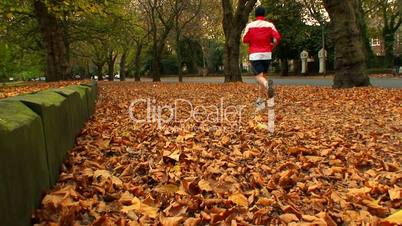 Young man jogging through the autumn leaves