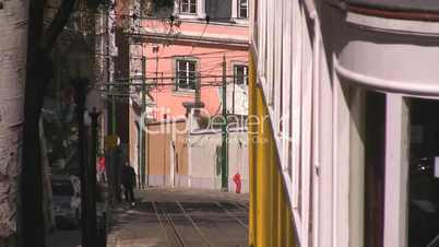 Zwischen Häusern bergabfahrende Tram in Lissabon
