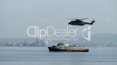 Military helicopter over a ship