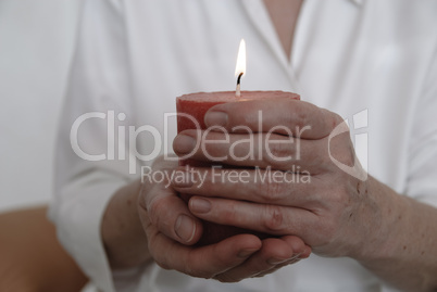 Frauenhände mit brennender Kerze