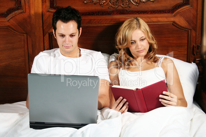 Laptop und Buch im Bett