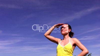 Young woman standing and looking around against the blue sky