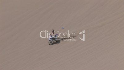 Motocrossfahrer fährt eine Sanddüne herunter
