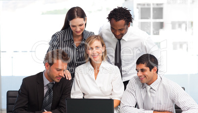 Multi-ethnic business people using a laptop in an office