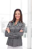Smiling young businesswoman with folded arms