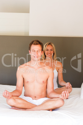 Smiling woman doing yoga on bed