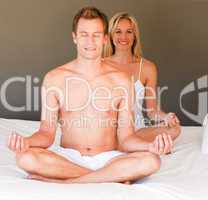 Young couple doing spiritual exercises on bed