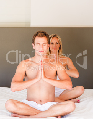 Attractive couple doing spiritual exercises on bed