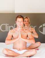Attractive couple doing spiritual exercises on bed