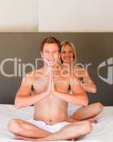 Young couple doing yoga moves on bed