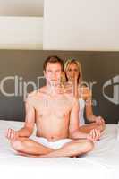 Young couple doing yoga on bed with copy-space