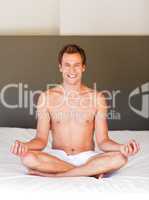 Smiling handsome man meditating on bed