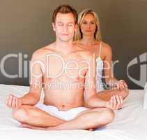 Young girl doing yoga on bed with her boyfriend