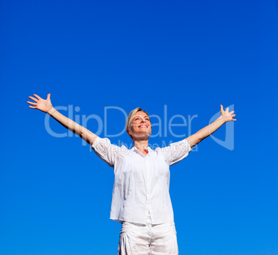 Young woman doing exercises against blue sky