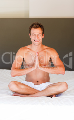 Smiling man meditating on bed