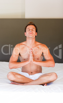 Handsome boy meditating on bed
