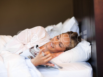 Young woman reading a magazine in bed