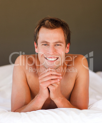 Young man relaxing in bed smiling at the camera