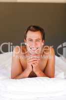 Smiling handsome boy lying in bed with copy-space