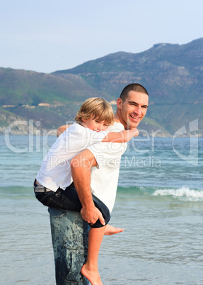 Father giving his son piggyback ride on the beach