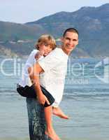 Father giving son piggyback ride on the beach
