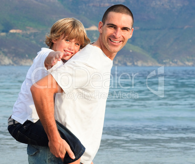 Father giving his son piggyback ride on the beach