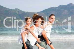 Couple giving children piggyback rides on the beach